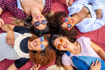 Four young women lying on blanket wearing sunglasses smiling