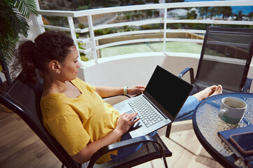 Woman Relaxing on a Balcony While Working on Laptop with Scenic Outdoor View