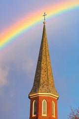 The uplifting sight of a rainbow arching over a church steeple, symbolizing God's covenant with humanity in a palette of soft pastel hues