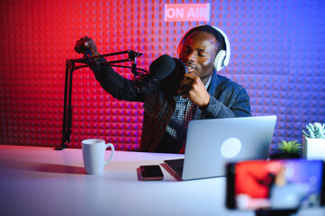 african american vlogger using smartphone to film podcast in studio. blogger with mobile phone,...