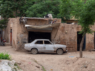 Abandoned Vehicle Parked Outside a Rustic Brick Workshop Building