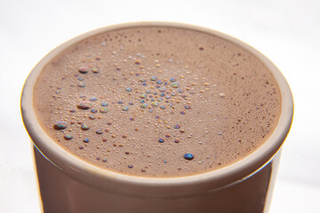 Close-up of a frothy coffee surface with vibrant, iridescent bubbles in a ceramic cup, showcasing a...