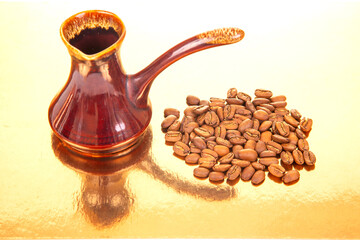 A glossy red ceramic Turkish coffee pot with a matching handle, surrounded by roasted coffee beans...