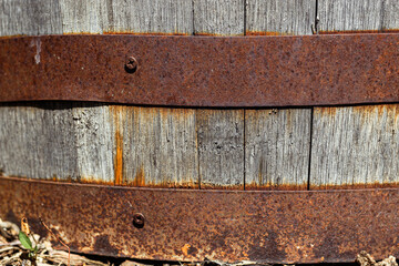 a close-up of an old wooden barrel held together with rusty metal hoops. weathered wood backdrop for garden, rustic charm, or other creative backgrounds