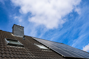 Fototapeta premium Photovoltaic panels providing green energy on rooftop with skylights and chimney