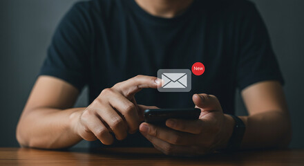 Man using smartphone with new email notification displayed on the screen in a dark setting view