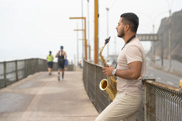 Saxophonist finding inspiration playing on the beach boardwalk