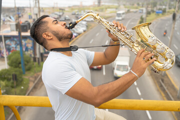 Young saxophonist playing on bridge overlooking highway seeking inspiration