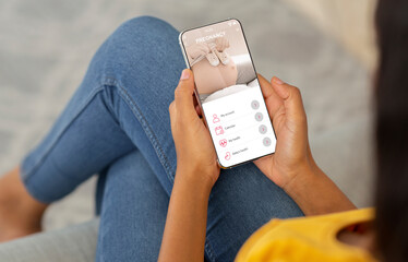 App For Future Moms. Over the shoulder view of black pregnant lady using mobile application for pregnancy control, tracking baby's development and health with digital calendar for females