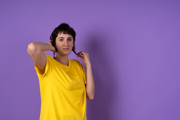 Young woman playing with pigtails on purple background