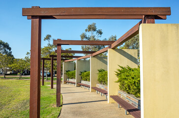 Contemporary timber pergola with built-in brick and timber benches in a communal garden courtyard...