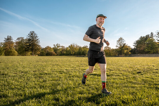 A smiling runner on a green grass field getting reading for a summer 5k race.  Strong and determined to run fast.