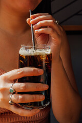 hand holding a glass of root beer with drinking straw
