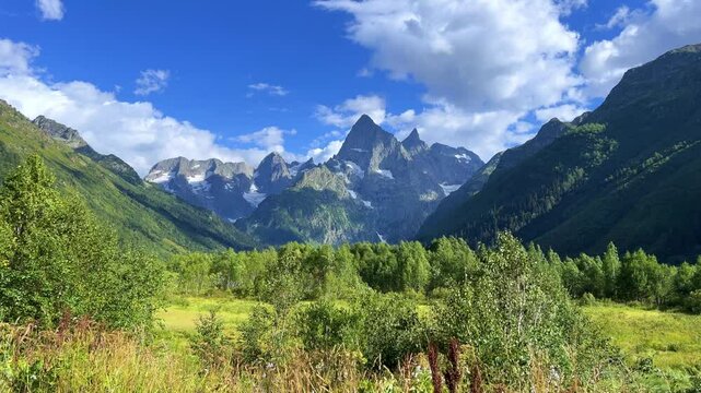 Teberdinsky Nature Reserve. View of Kosygin's glade in the Gonachkhir gorge and the top of Dombai-Ulgen mountain near Lake Tumanly-Kel on a sunny summer day. Panoramic landscape. Resort. 4K