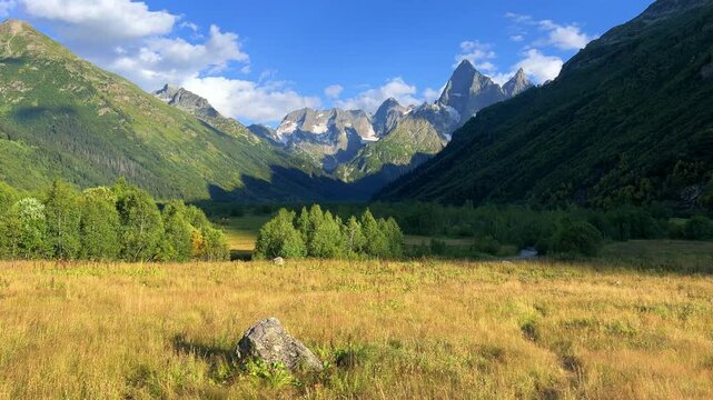 Teberdinsky Nature Reserve. View of Kosygin's glade in the Gonachkhir gorge and the top of Dombai-Ulgen mountain near Lake Tumanly-Kel on a sunny summer day. Panoramic landscape. Resort. 4K
