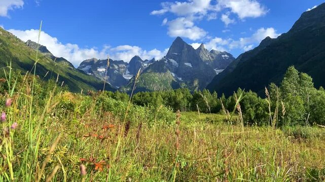 Teberdinsky Nature Reserve. View of Kosygin's glade in the Gonachkhir gorge and the top of Dombai-Ulgen mountain near Lake Tumanly-Kel on a sunny summer day. Panoramic landscape. Resort. 4K