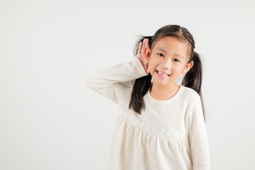 Portrait Asian young child smiling overhearing listening sound to gossip with attention with hand on ear studio shot isolated on white background with copy space hearing gesture, kindergarten kid girl
