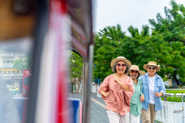 Happy Asian senior woman tourist travel Bangkok city, Thailand on summer holiday vacation. Elderly women friends enjoy outdoor lifestyle travel in the city by three wheeled vehicles Tuk Tuk taxi.