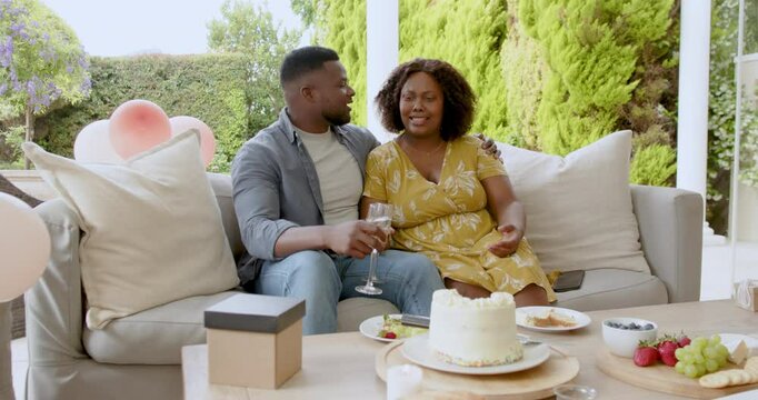 African American couple enjoying wine and cake on patio, sharing loving moment