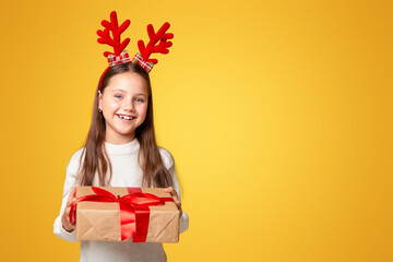 Emotions of happiness from Christmas. Smiling little kid with horns in sweater with gift, isolated...