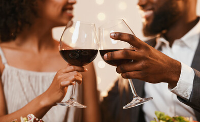 Cheers. Cropped of afro couple celebrating St. Valentine's Day at restaurant, drinking red wine