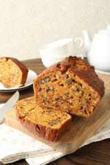 Cut homemade carrot cake with nuts on wooden table, closeup