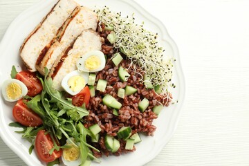 Delicious salad with brown rice on white wooden table, top view