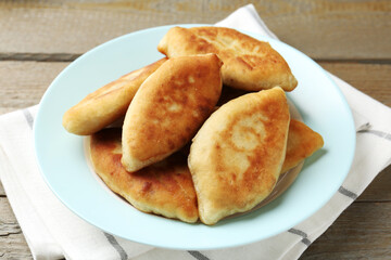 Delicious fried pyrizhky (stuffed pies) on wooden table