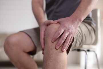 Man suffering from knee pain at home, closeup