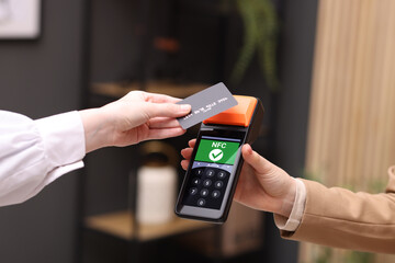 Payment terminal with NFC system. Client using credit card to pay for service indoors, closeup