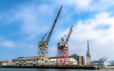 Old industrial cranes and warehouse sit in an abandoned state in an old port