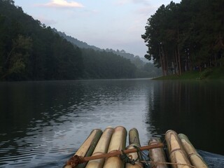 Bamboo Raft on Misty Lake with Lakeside Camping and Pine Trees