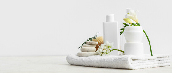 Composition with cosmetic products, spa accessories and flowers on light background