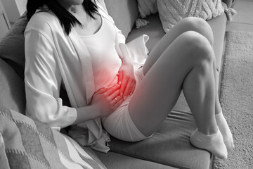 Young woman suffering from severe abdominal pain at home