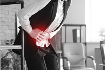Young businesswoman suffering from severe abdominal pain in office, closeup