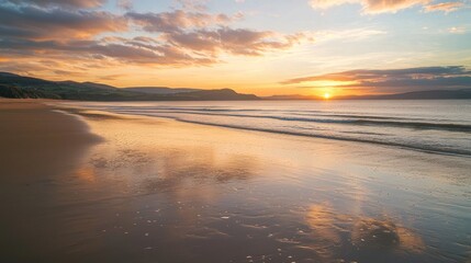 Obraz premium A sunset over a calm beach with gentle waves