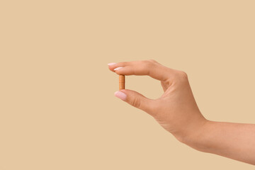 Woman holding brown pill on yellow background