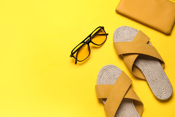 Stylish yellow sandals with purse and sunglasses on color background