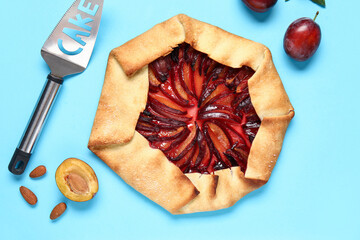 Delicious plum galette and almond on blue background