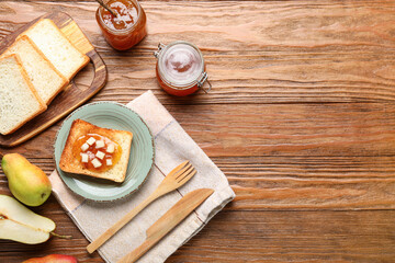 Plate with tasty pear jam and bread on wooden background