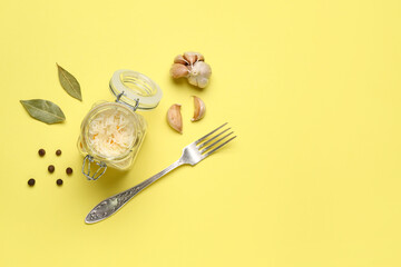 Jar with tasty sauerkraut and ingredients on yellow background
