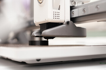 Close up and low angle shot of white modern design 3D printer nozzle head print a black model on build plate. Product design, STEM education, technology, maker concept.