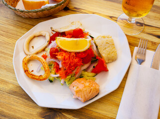 Seafood salad with grilled squid, salmon, lettuce, tomatoes and carrot