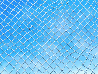 Chain link fence creating a unique pattern and texture in an urban environment with tangled fishing nets nearby