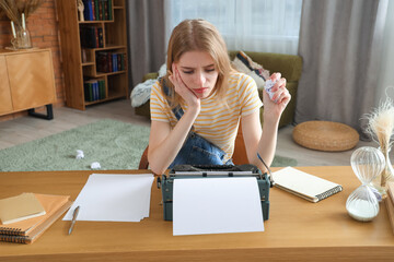Displeased female author with vintage typewriter crumpling paper at table in office