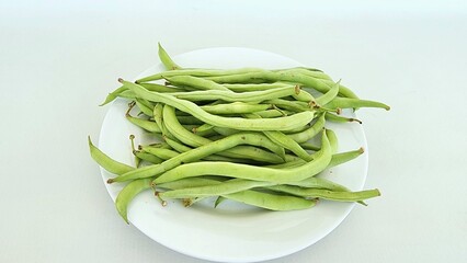 baby green beans or mini green beans on a white plate, isolated on white background