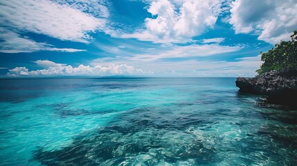 Fototapeta premium Vibrant Blue Ocean Water Under Cloudy Sky Horizon And Green Vegetation