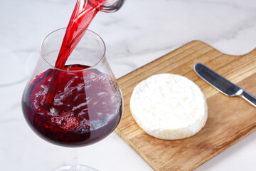 Wine Pouring with camembert cheese on the wooden cutting board on the table
