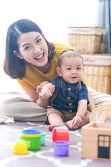 Asian woman with her son holding him by her hand. Happy asian baby boy was holding by his mother. Asian family with little boy at home enjoy tender carefree family moment, motherhood