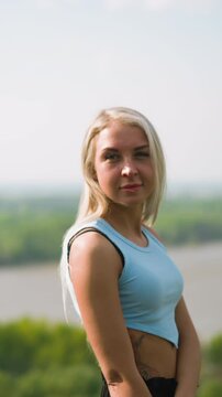 Pretty woman turns head and smiles to beloved man motorcyclist at romantic date on hilly bank of large river on sunny spring day slow motion